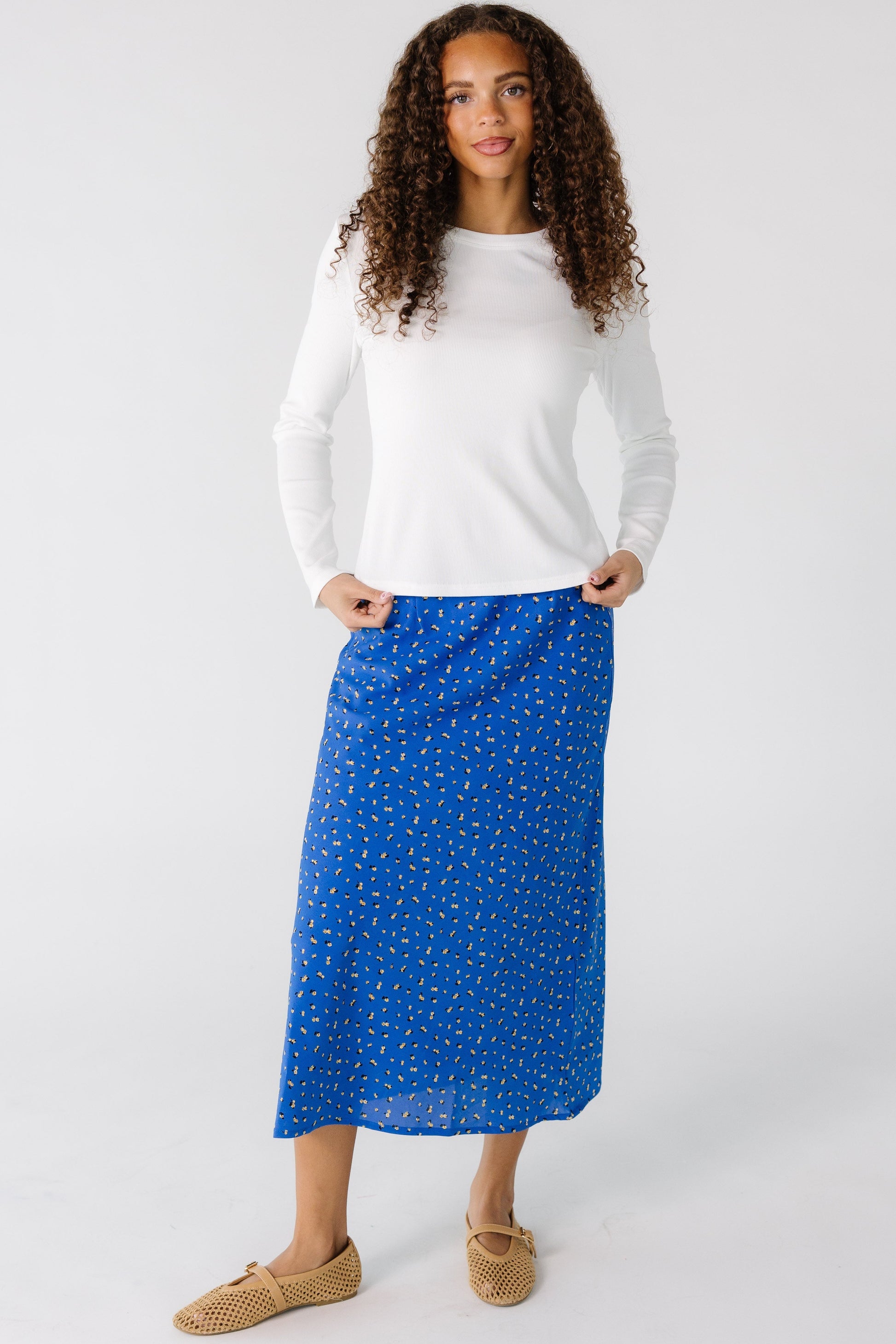 Teen girl wearing a blue floral A-line midi skirt.