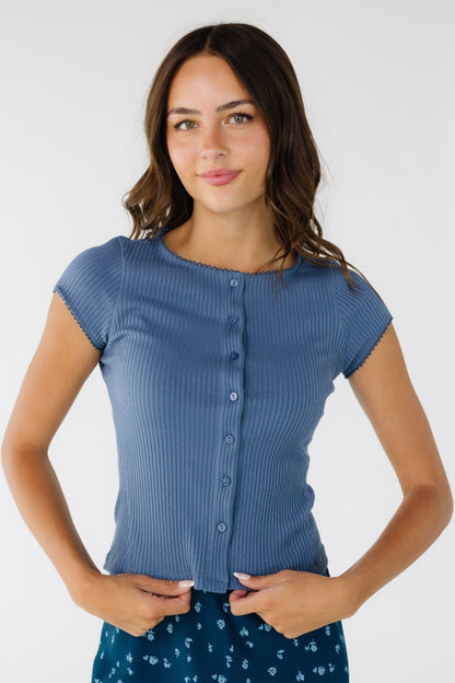Young woman wearing a modest button down, rib knit top with lace trimmed cap sleeve 