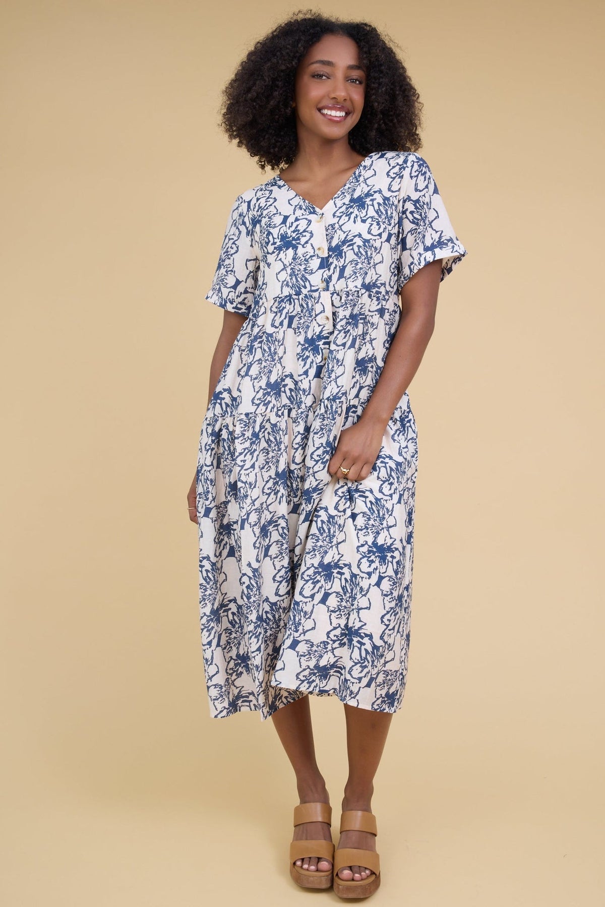 Young woman wearing a modest blue & crema floral midi dress with a V-neckline and short sleeves.