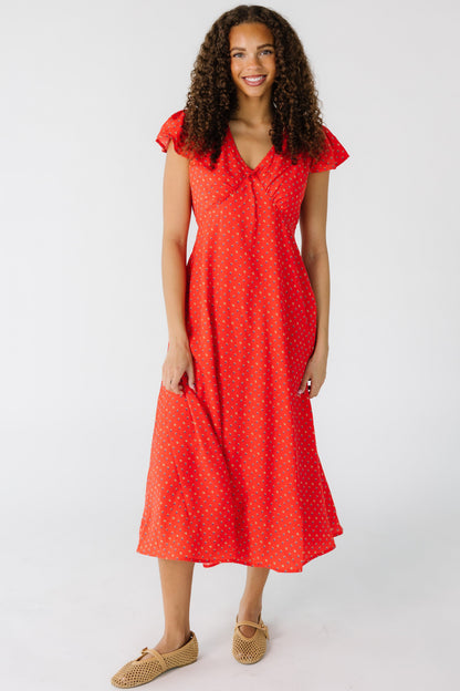 Teen girl wearing a modest red print midi dress with a V-neckline and short flutter sleeves.