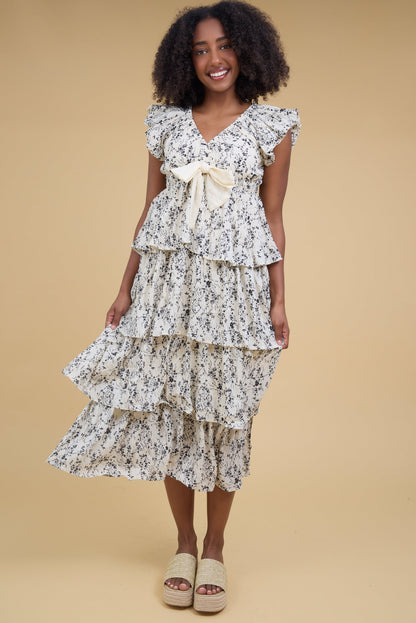 Young woman wearing a modest  off white  midi dress with a V-neckline, gathered cap sleeves and loose layered tier skirt.