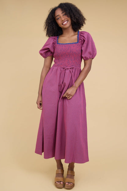 Young woman wearing a modest red & blue gingham midi dress with a smocked bodice and balloon sleeves.