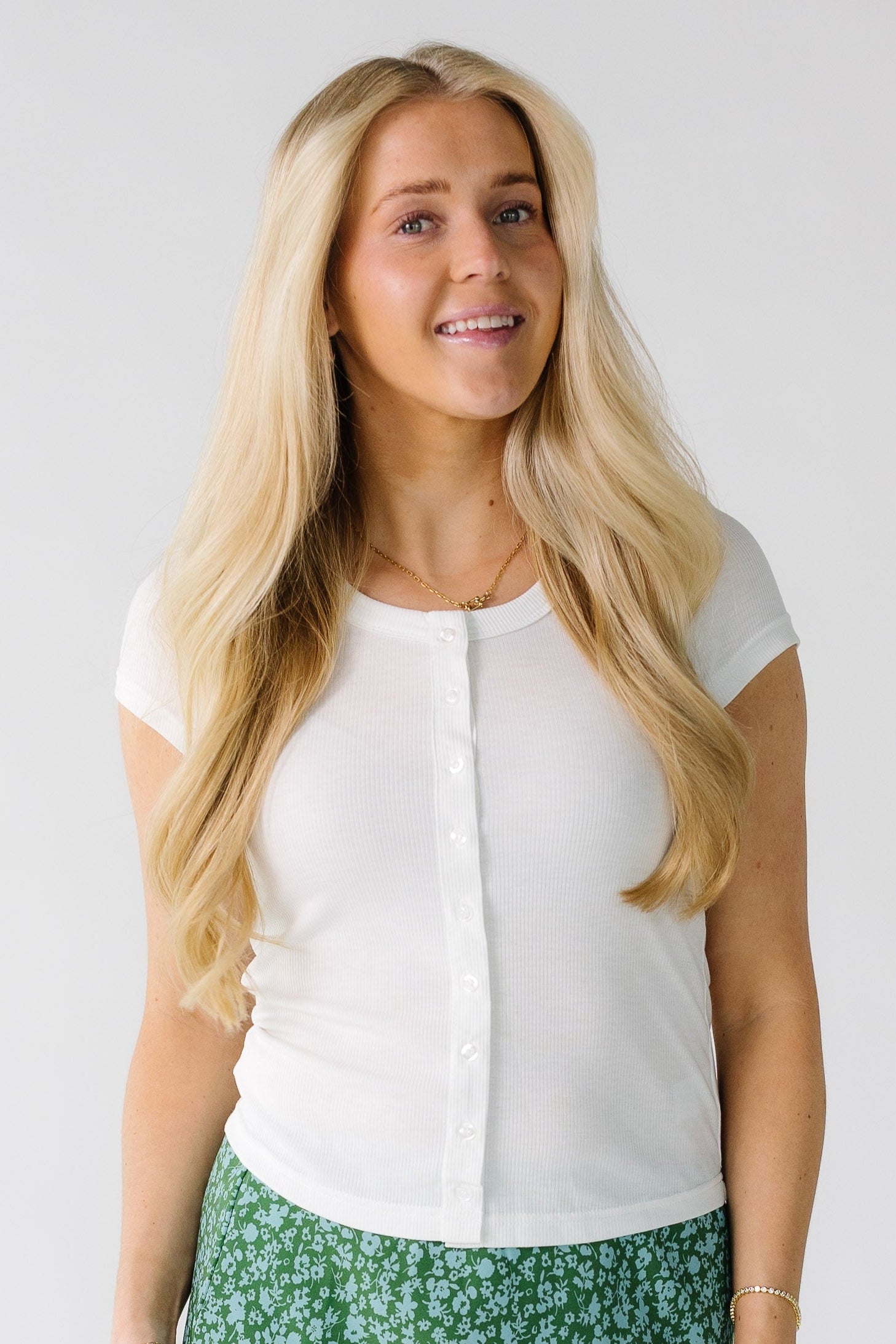 Woman wearing a close fitting white ribbed button down tee.