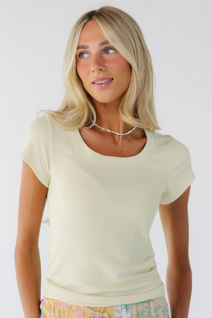 Woman wearing a soft yellow short sleeve tee with a ribbed scoop neckline.