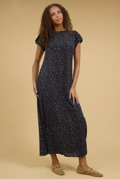 Teenage girl wearing a modest black floral maxi dress with a gathered cap sleeves and a round neckline.
