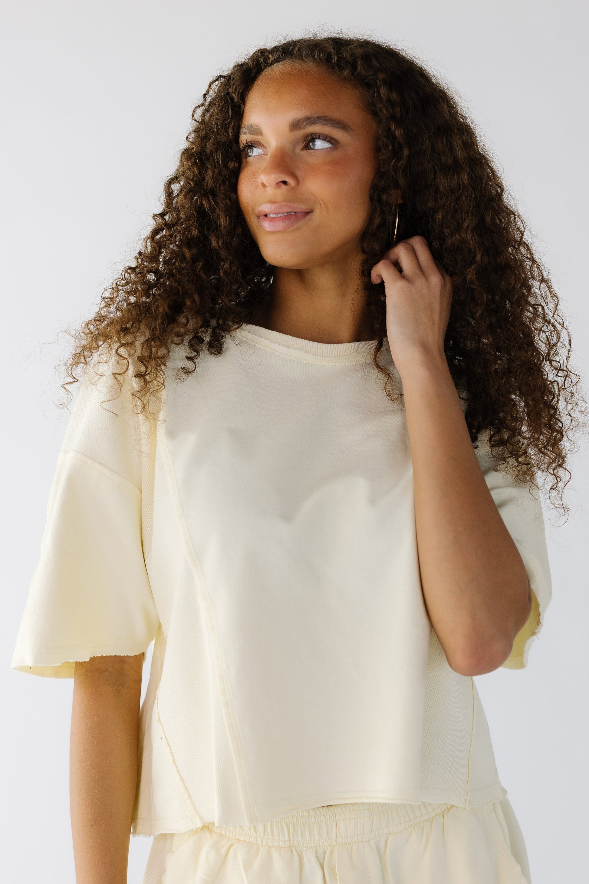 Teen girl wearing a yellow loose fitting tee with elbow length sleeves and rolled hems