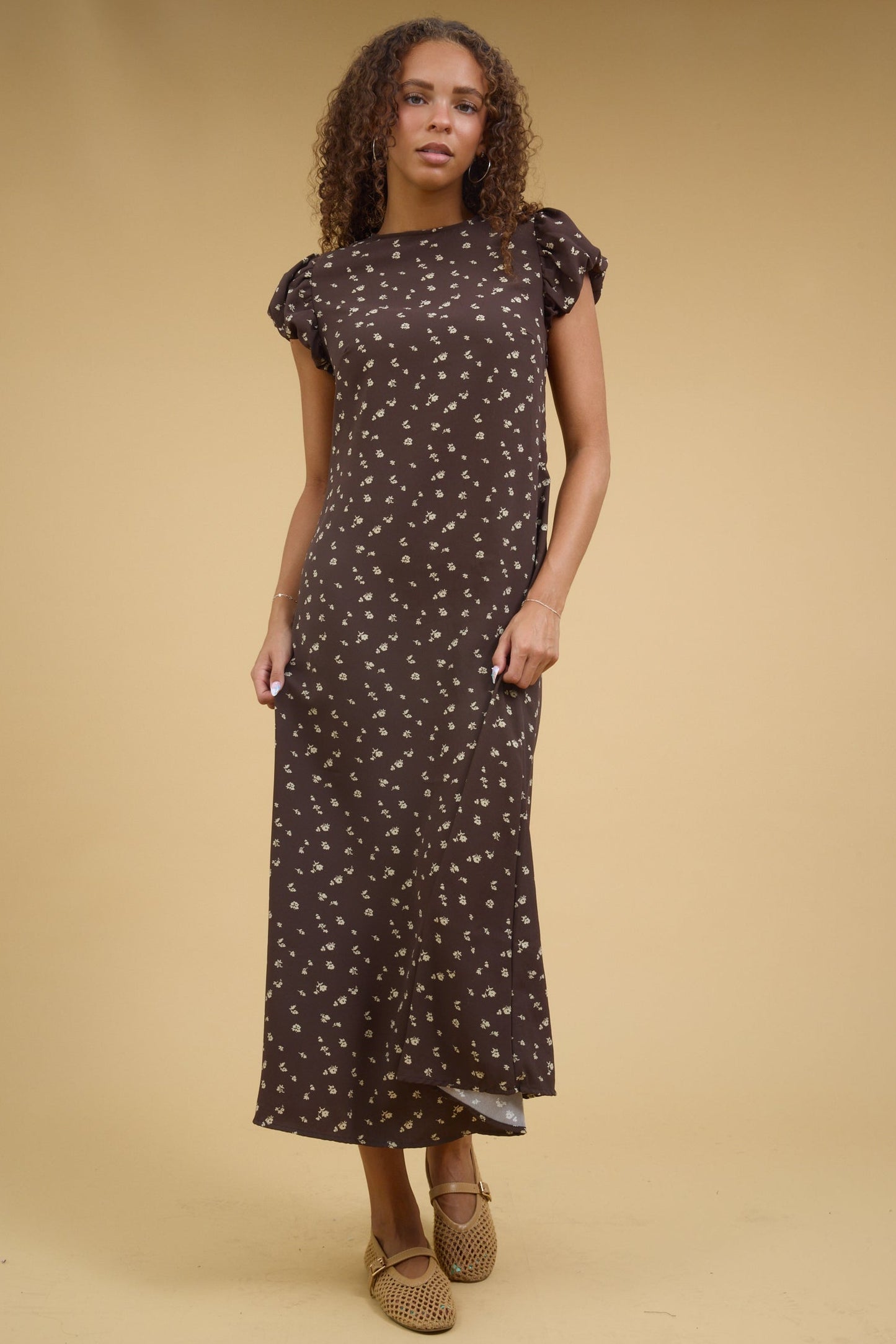 Teenage girl wearing a brown floral print midi dress wtih short gathered cap sleeves.