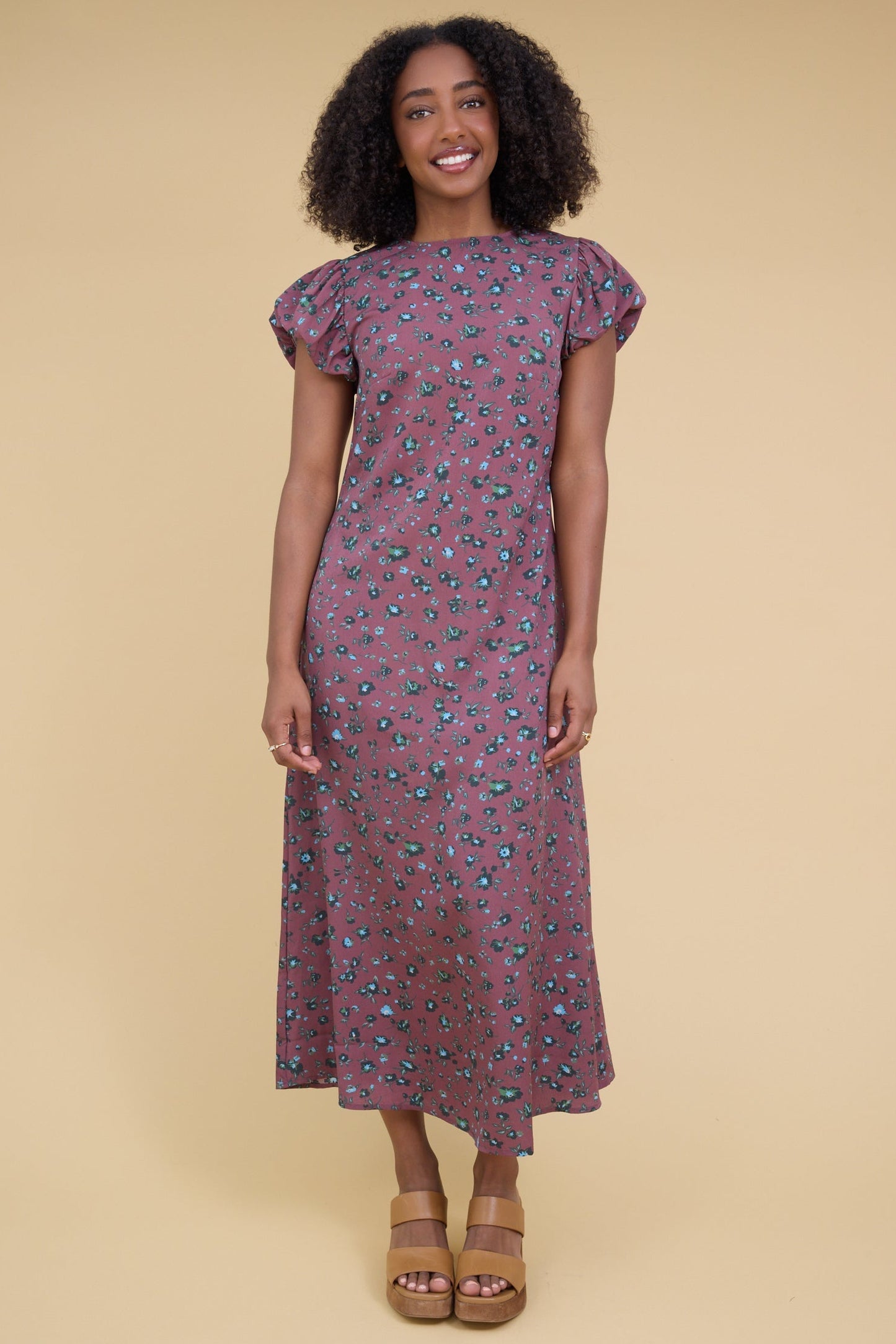 Young woman wearing a modest magenta midi dress with a round neckline nad gathered cap sleeves.