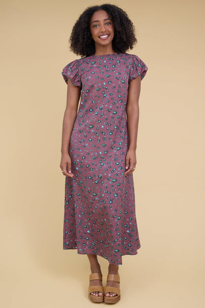 Young woman wearing a modest magenta midi dress with a round neckline nad gathered cap sleeves.