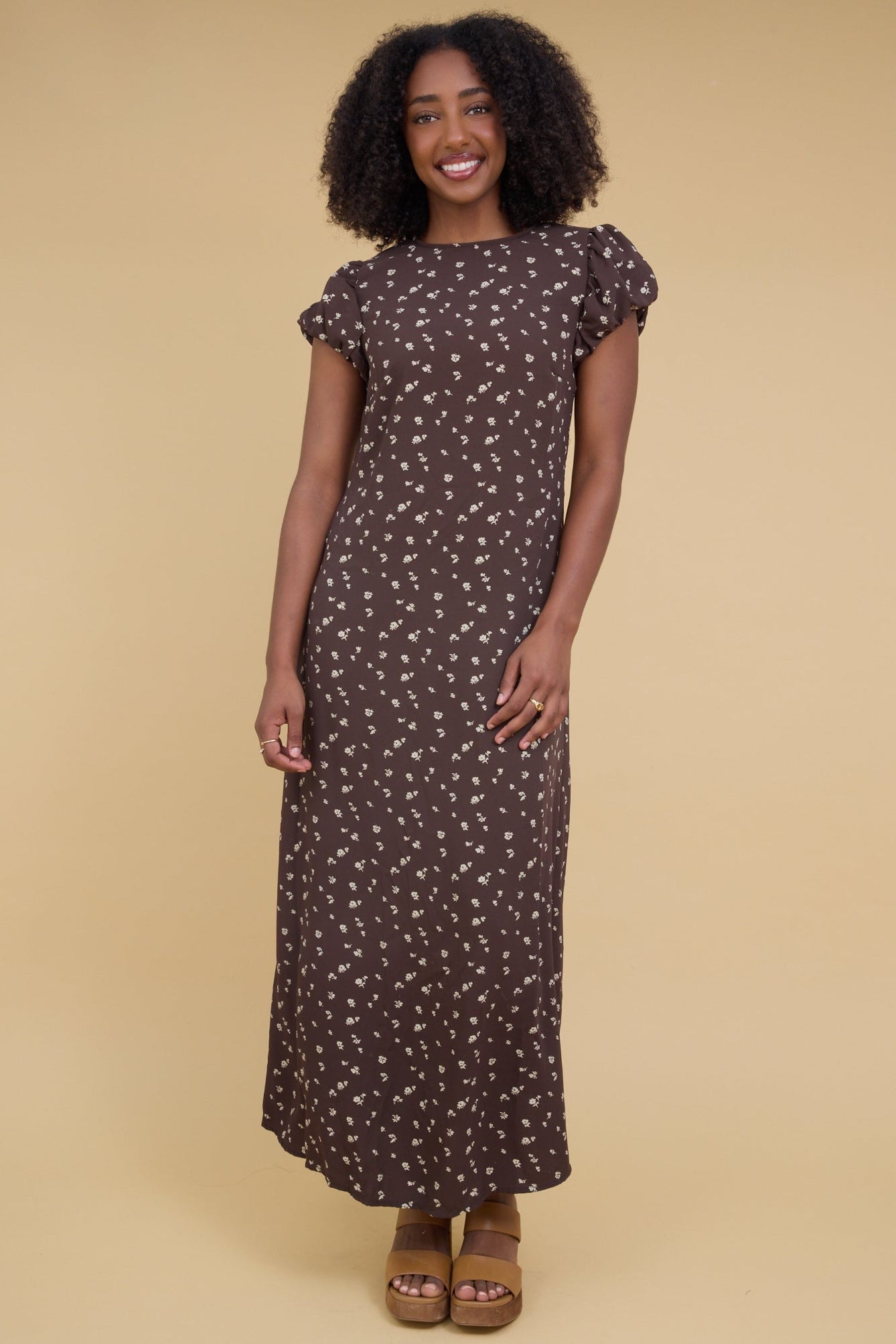 Young woman wearing a close fitting maxi dress with short gathered cap sleeves and a round neckline.