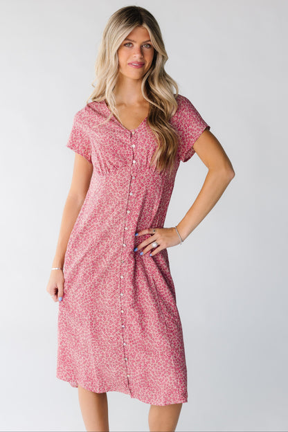 A woman wearing a pink floral dress with short sleeves