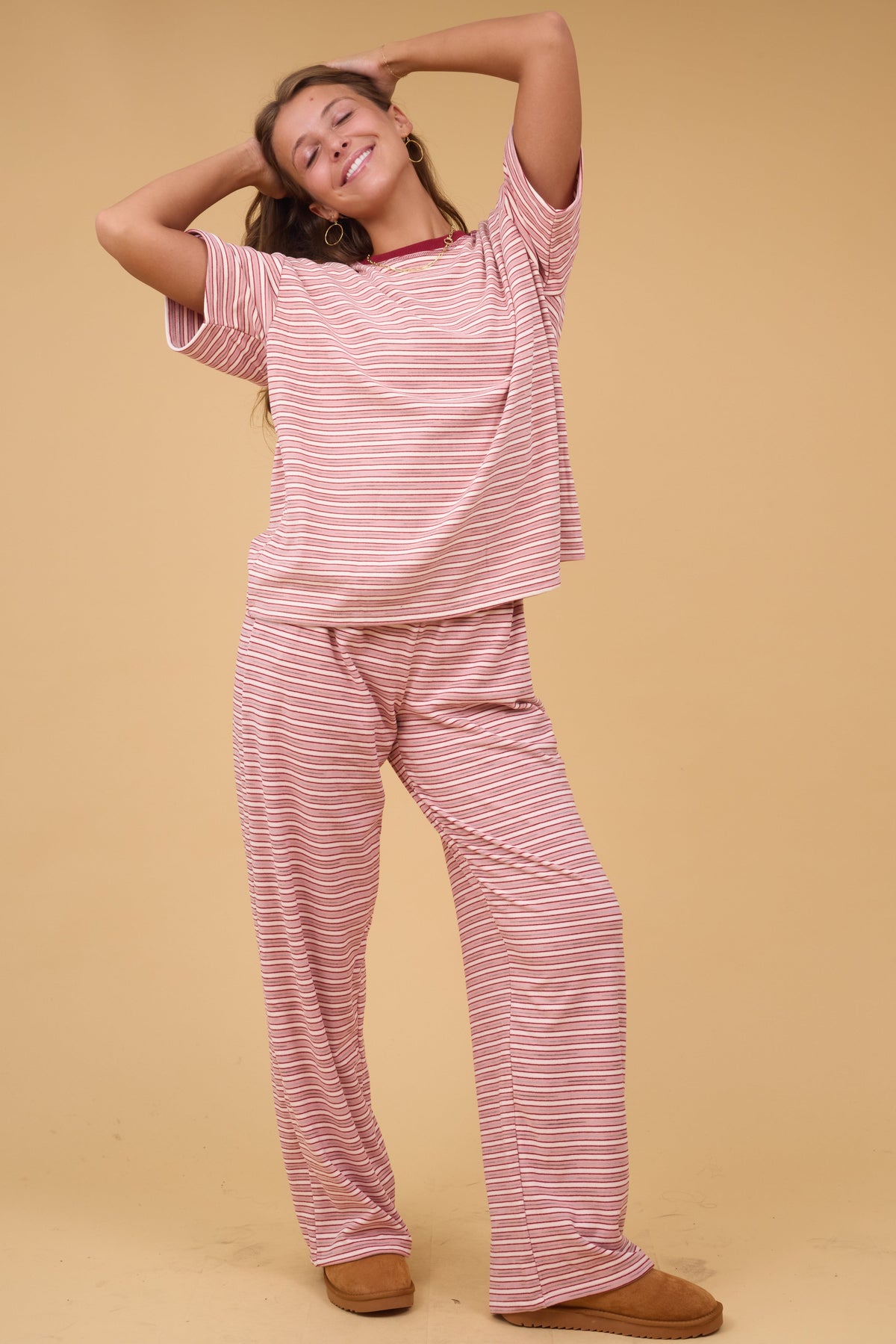 Young woman wearing pink stripe plush lounge pants with an elastic waist.