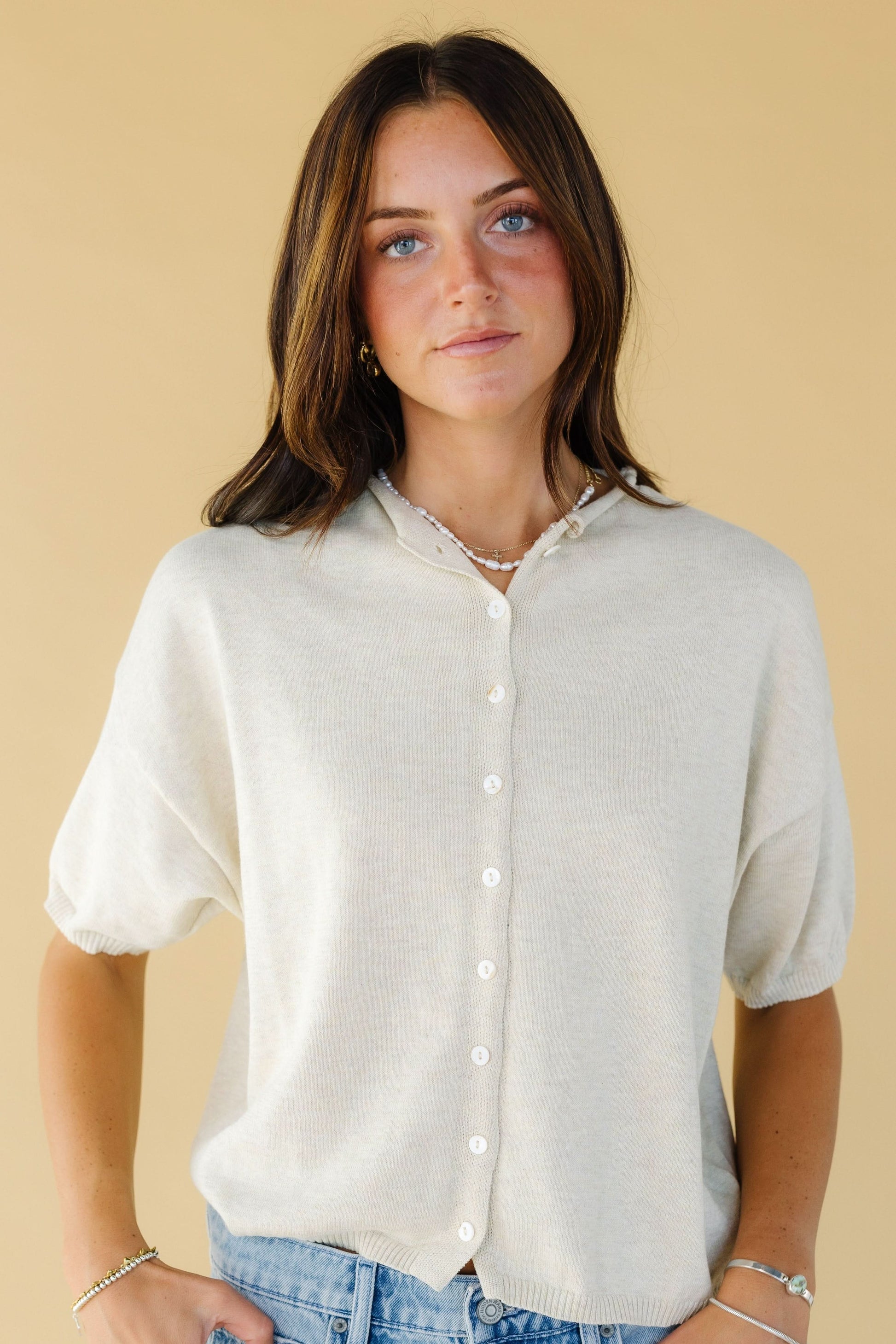Young woman wearing a modest button down cardigan in butter yellow with short sleeves.