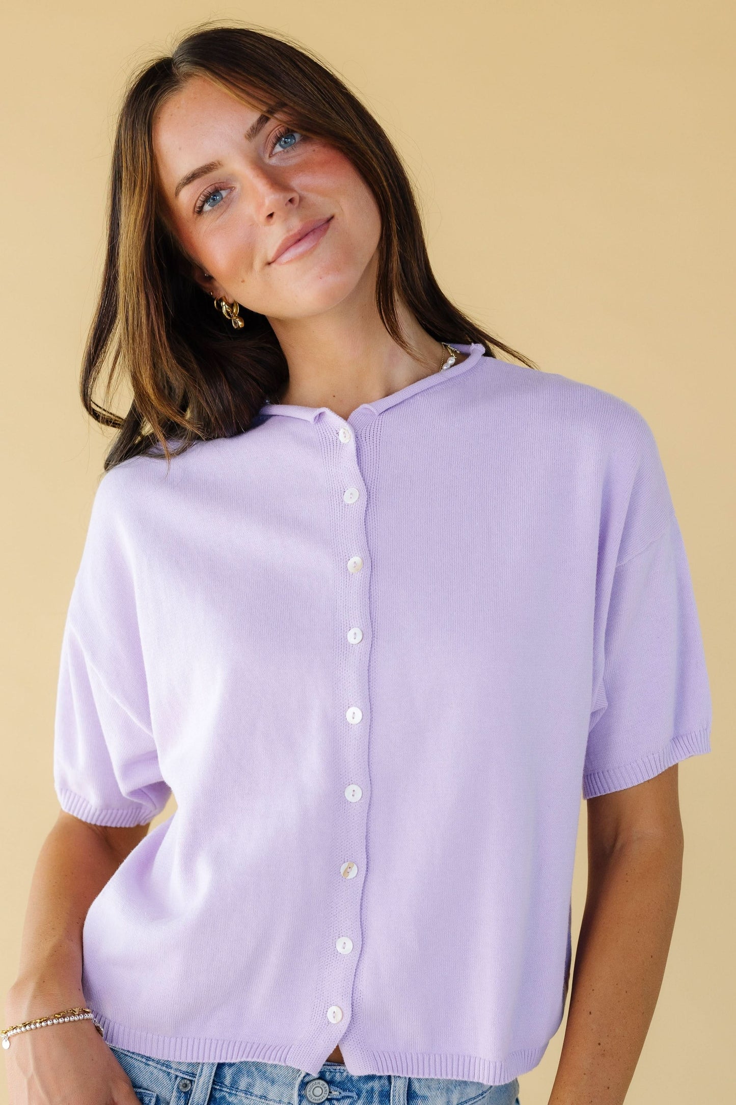 Young woman wearing a modest lavender button down cardigan with a rolled, round neckline and short sleeves.