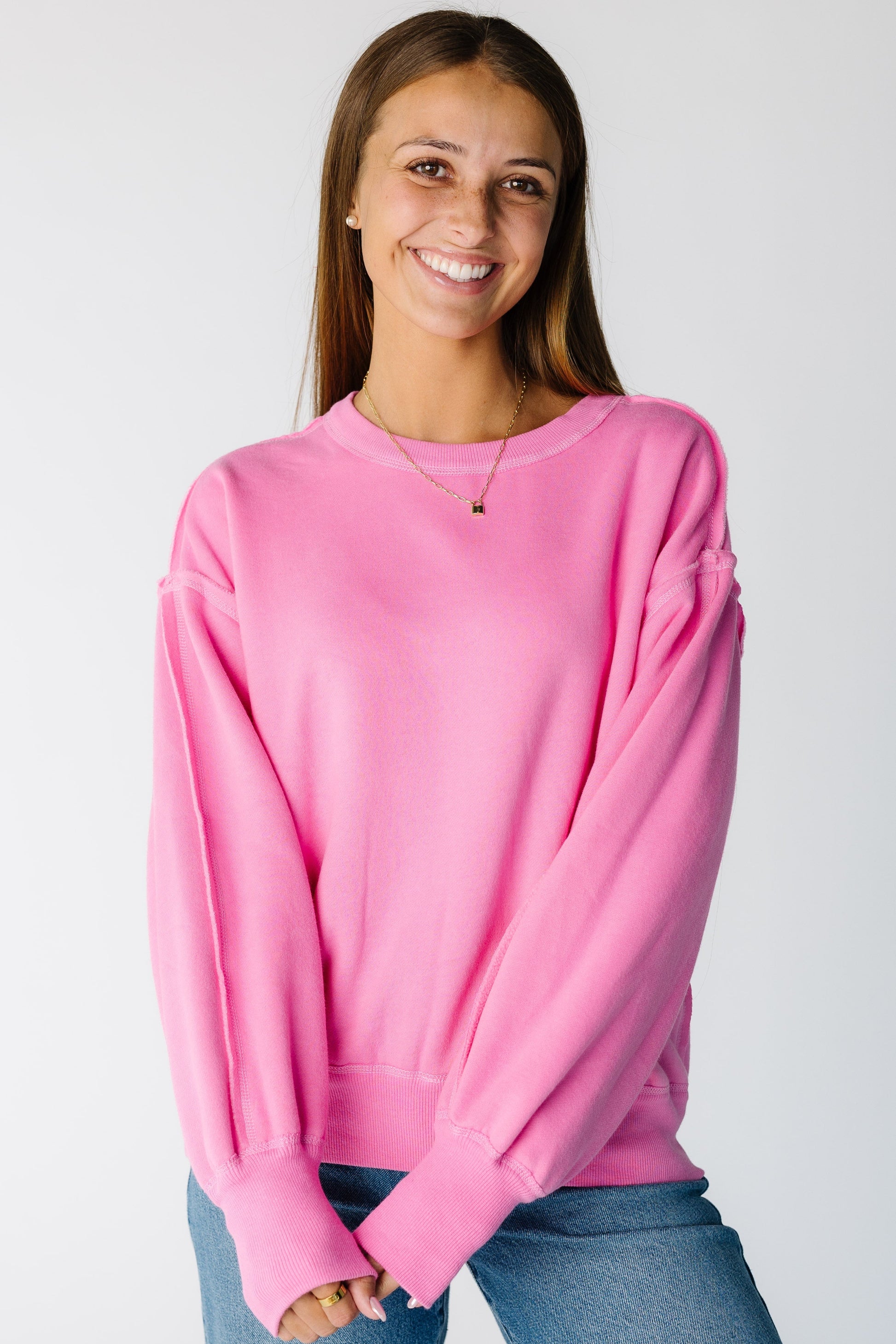 Woman wearing a pink long sleeve sweatshirt with wide ribbed cuffs