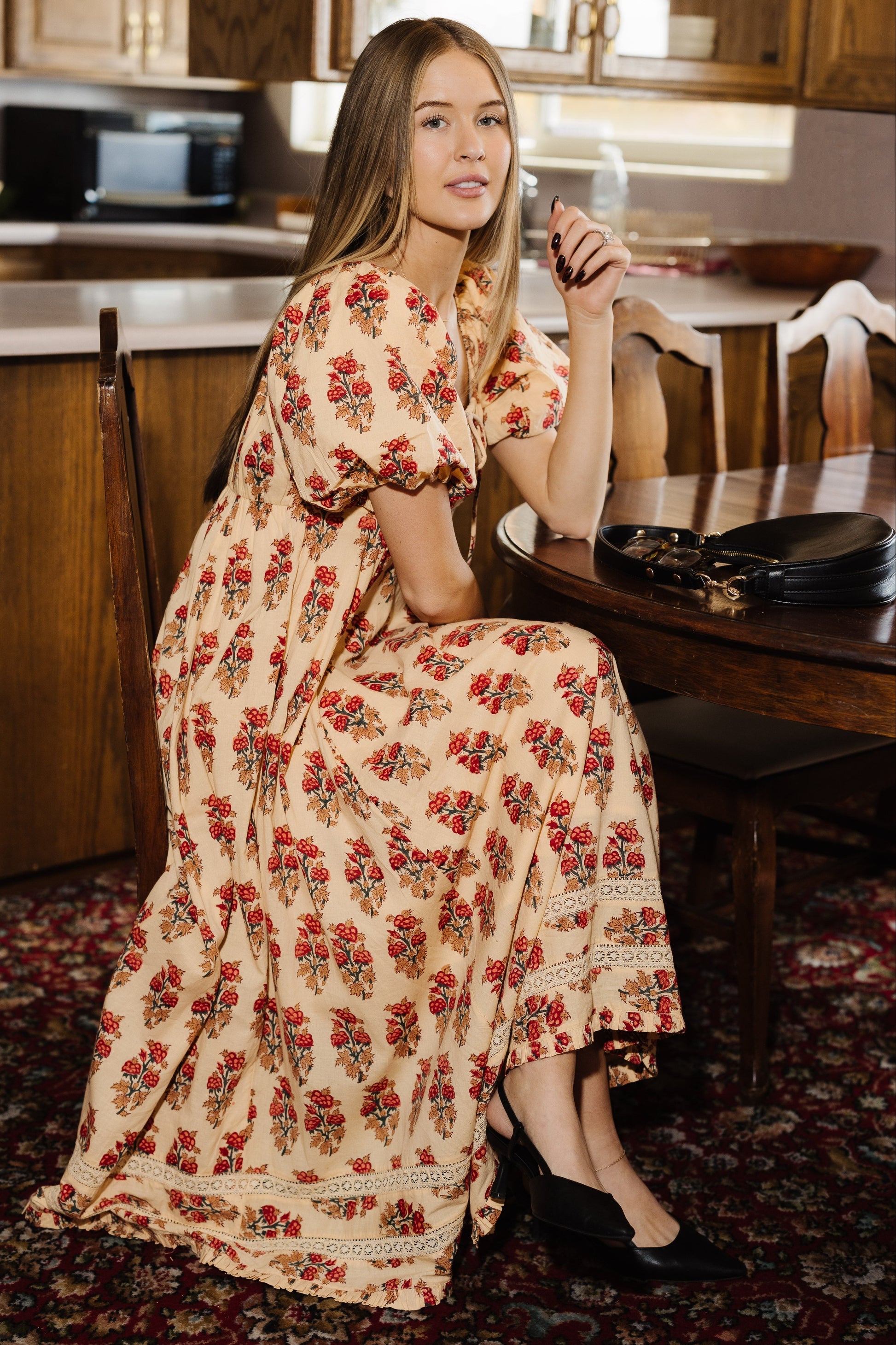 Woman wearing a floral midi dress in cream and rust.
