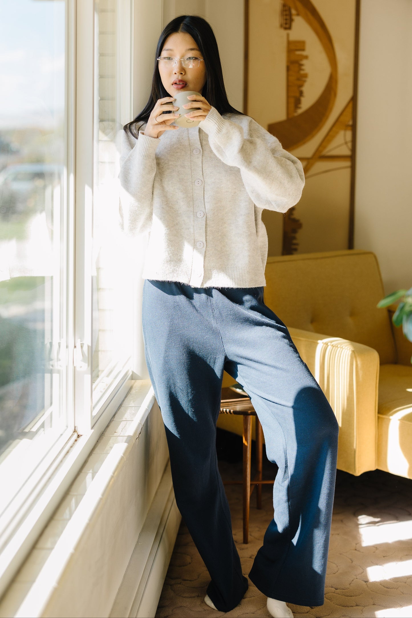 Woman wearing a pair of navy waffle knit wide leg lounge pants and a grey button down cardigan