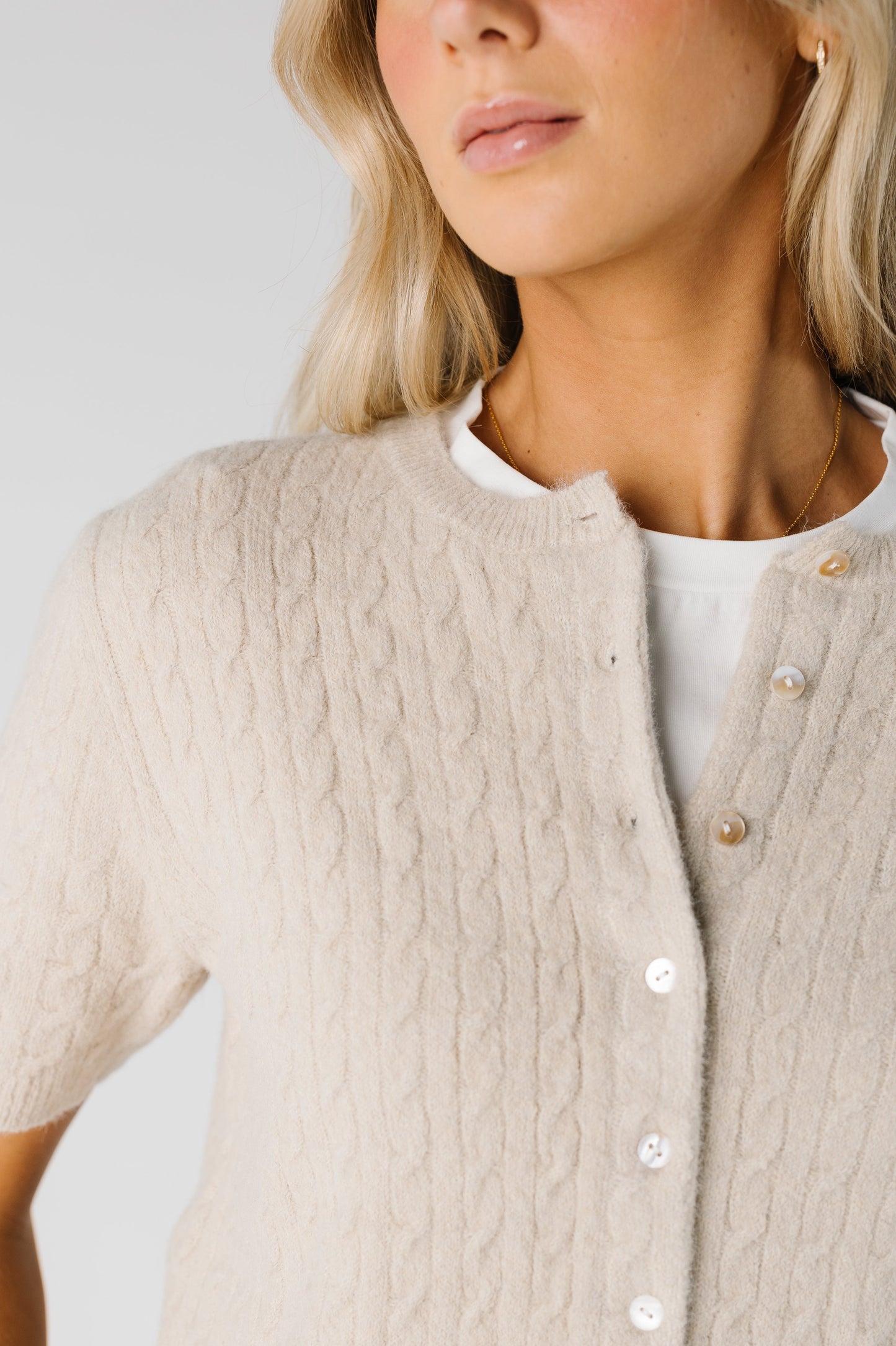 Close view of short sleeve cable button cardigan in tan