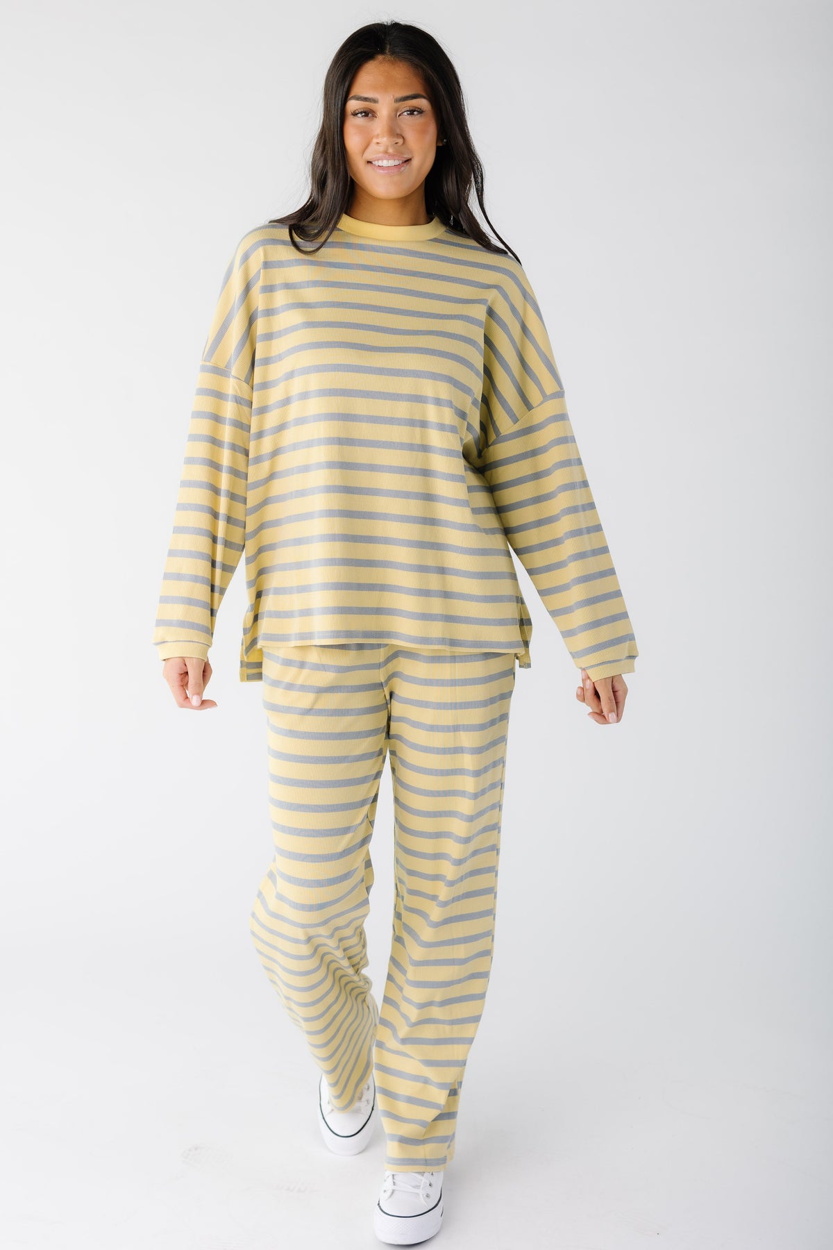Young woman wearing a modest yellow and blue ribbed lounge set with loose long sleeves and long wide leg pants.
