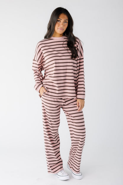 Woman wearing a modest loose fitting ribbed lounge set in pink and brown with long sleeves and a crew neckline.