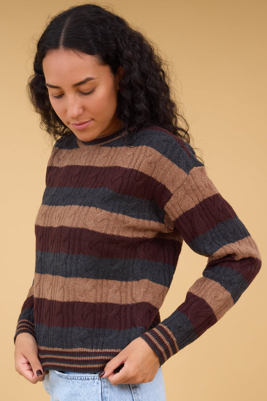 Young woman wearing a modest cable knit & 3 color stripe sweater with ribbed cuffs & waist.