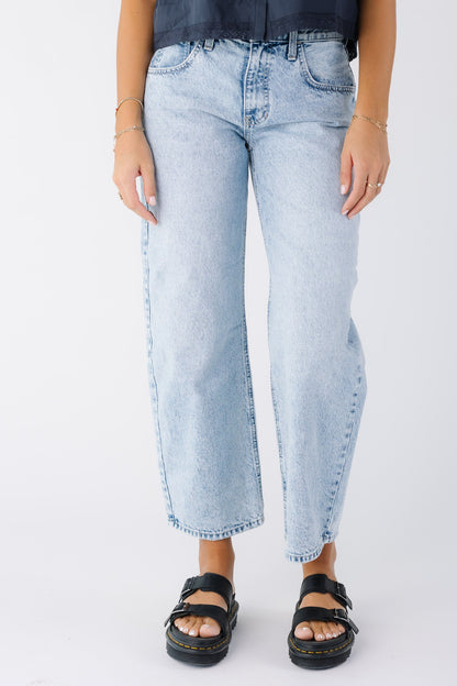 Young woman wearing wide leg barrel jeans in light denim.