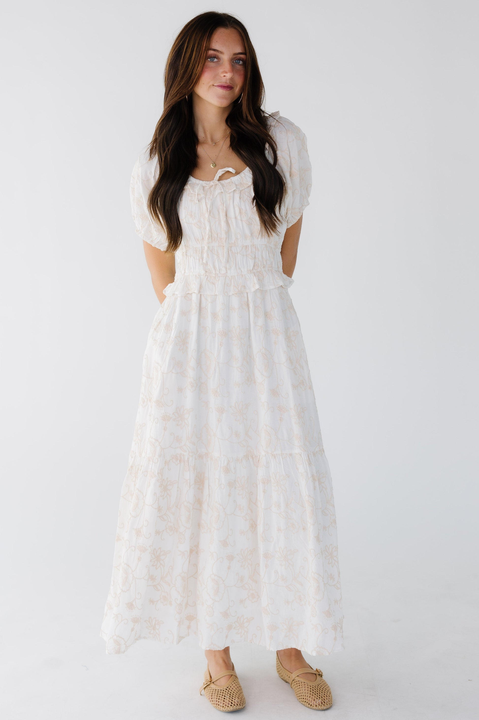 Young woman wearing a modest white with champagne color embroideryand a wide waistband and short sleeves.