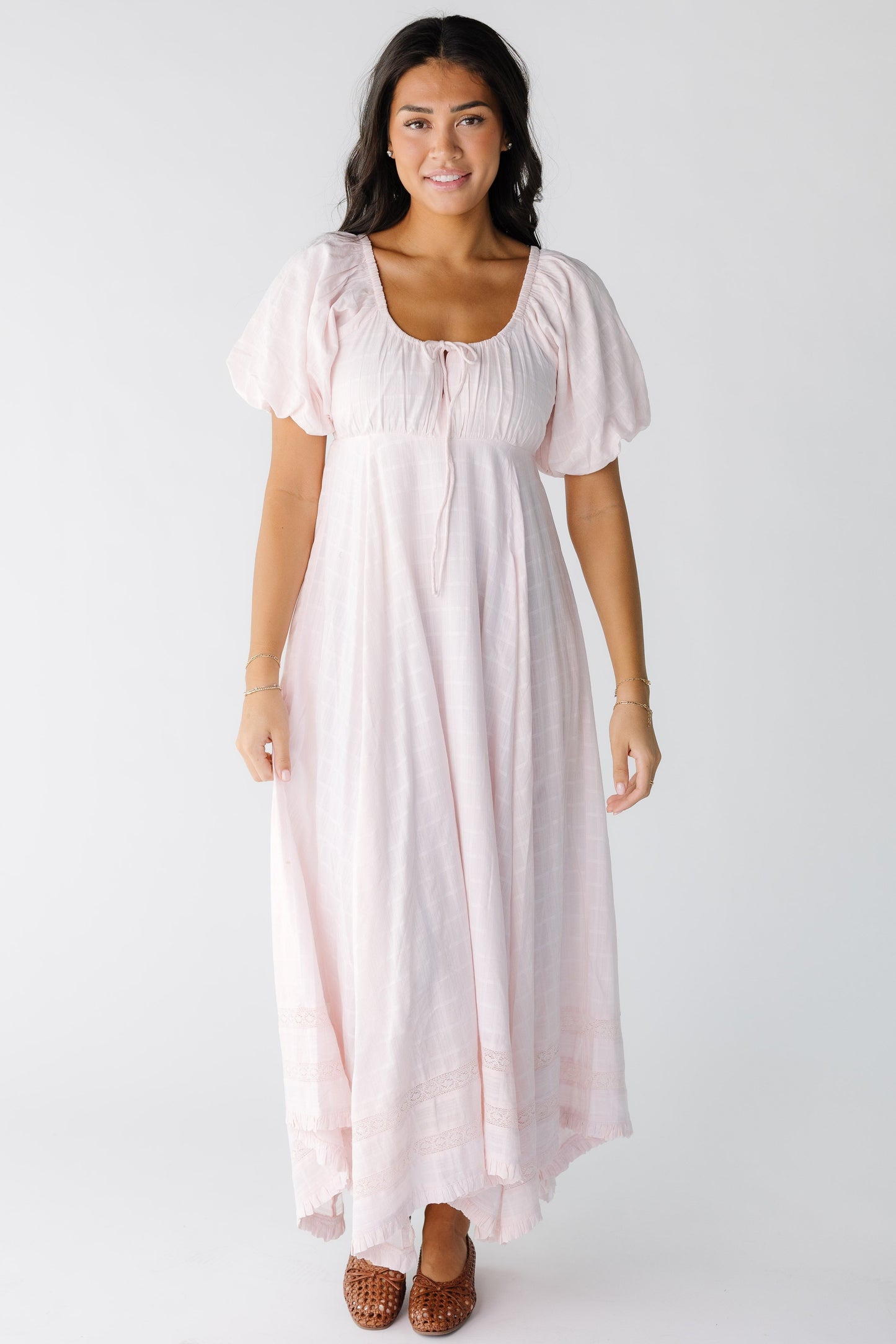 Young woman wearing a modest light pink midi-maxi dress with a scoop neckline with balloon sleeves and a snug gathered waist and flowy skirt.