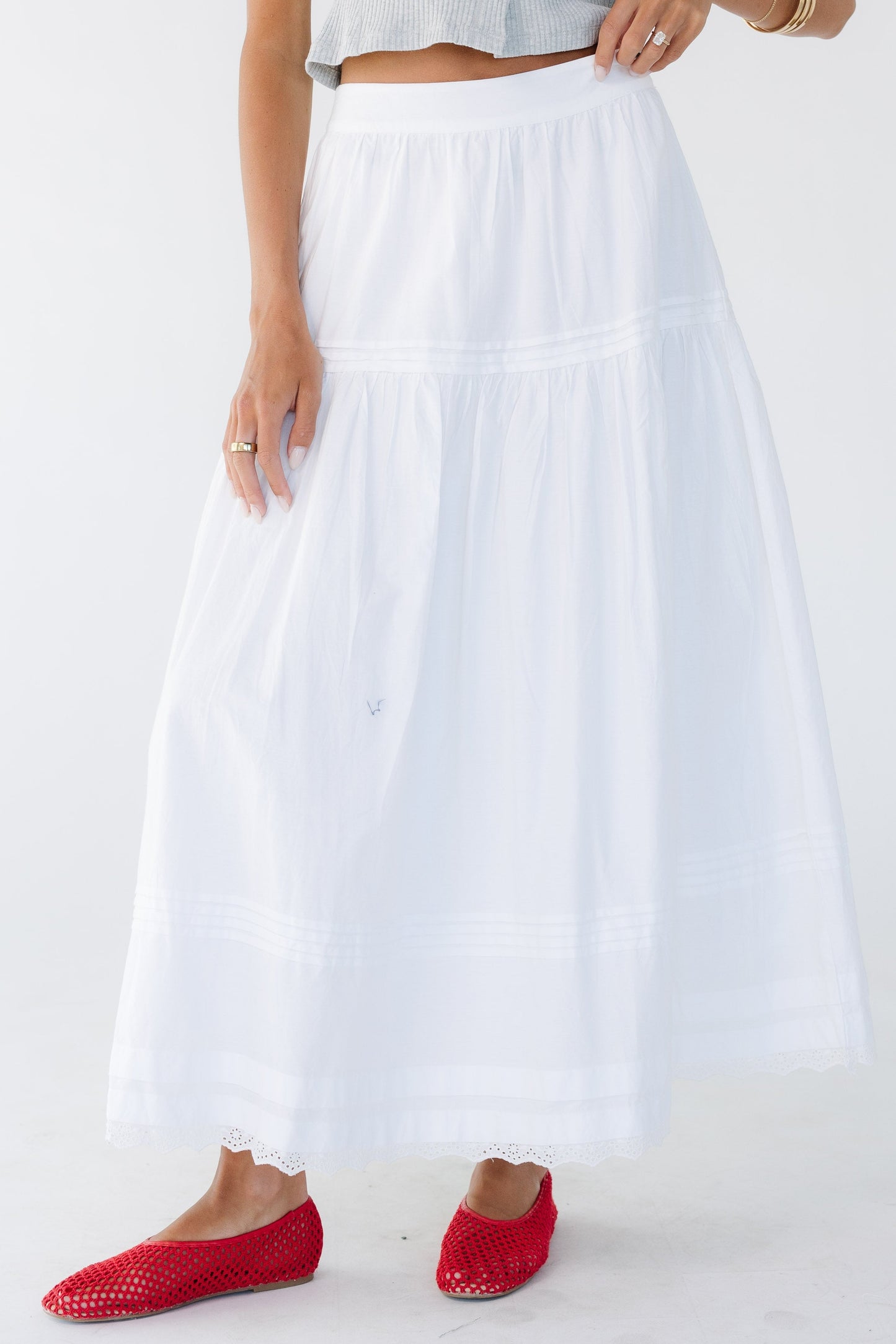 Young woman wearing a modest white midi-maxi skirt with a wide waistband, tier & lace details.