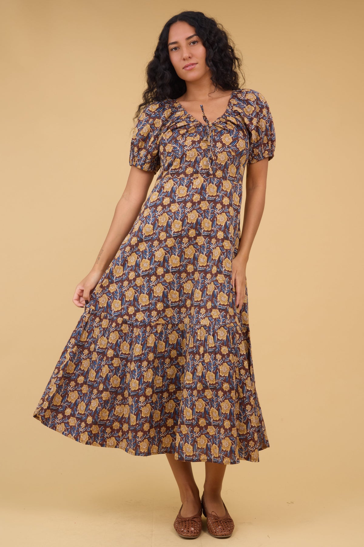Yougng woman wearing a modest floral print midi dress with a wide bottom ruffle, short puff sleeves, drawstring scoop neckline and empire waist.