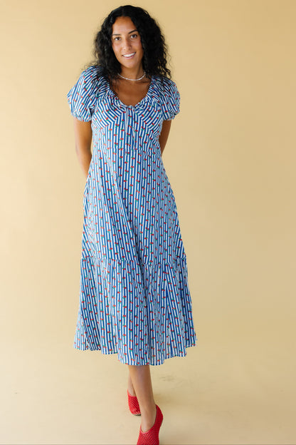 Young woman wearing a blue & white stripe with cherry print midi-maxi dress with puff sleeves and drawstring & elastic scoop neckline and a wide bottom ruffle.