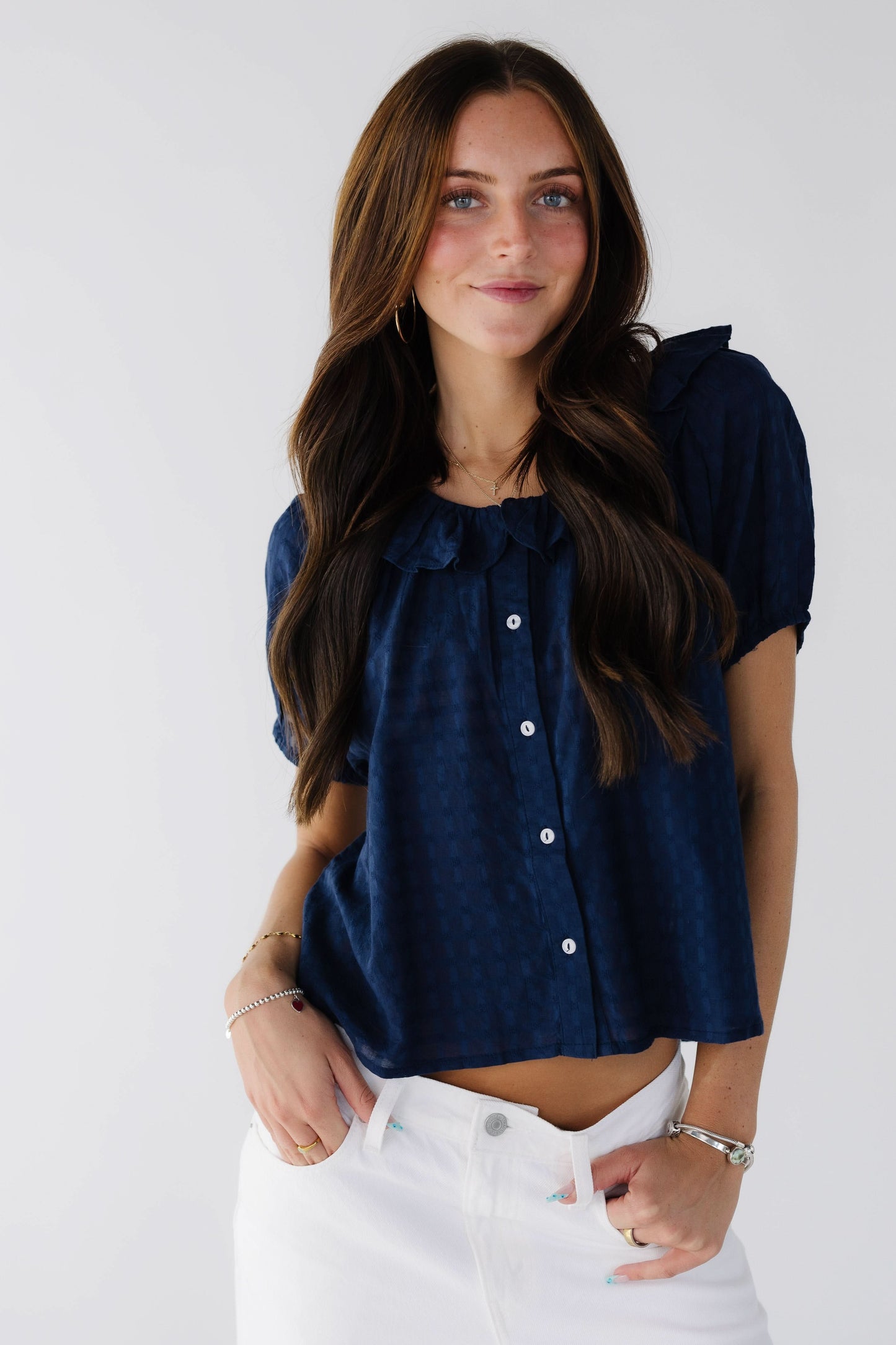 Young woman wearing a modest navy button down blouse with a ruffle collar and short sleeves.