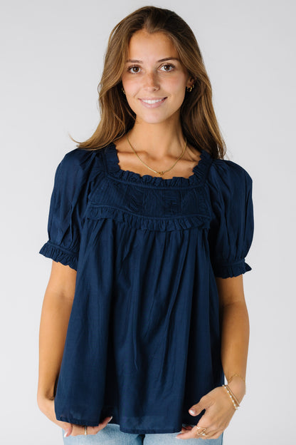 Woman wearing a modest navy blouse with a square neckline and short sleeves