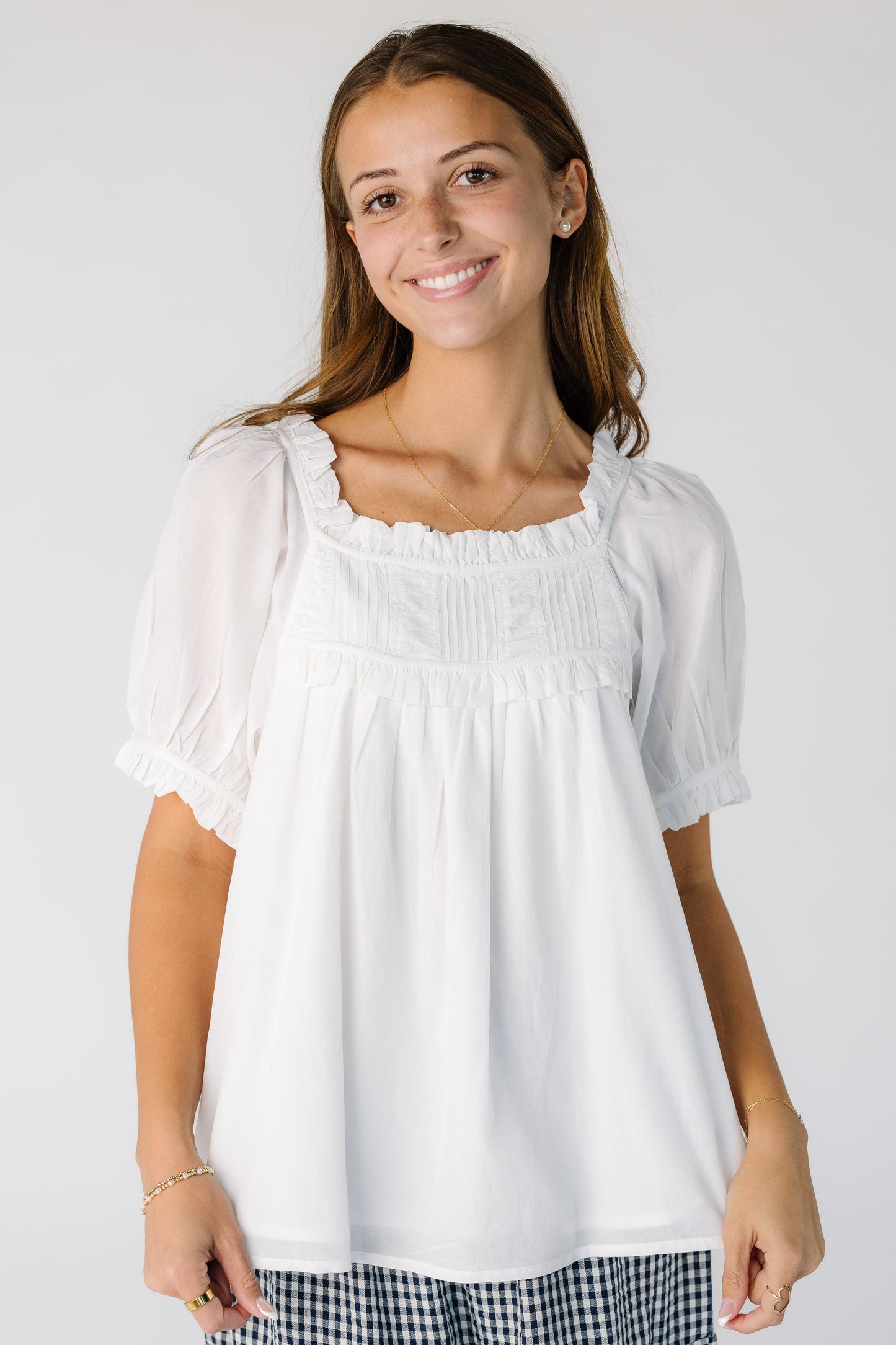 Woman wearing a modest white blousy top with a square neckline and short puff sleeves