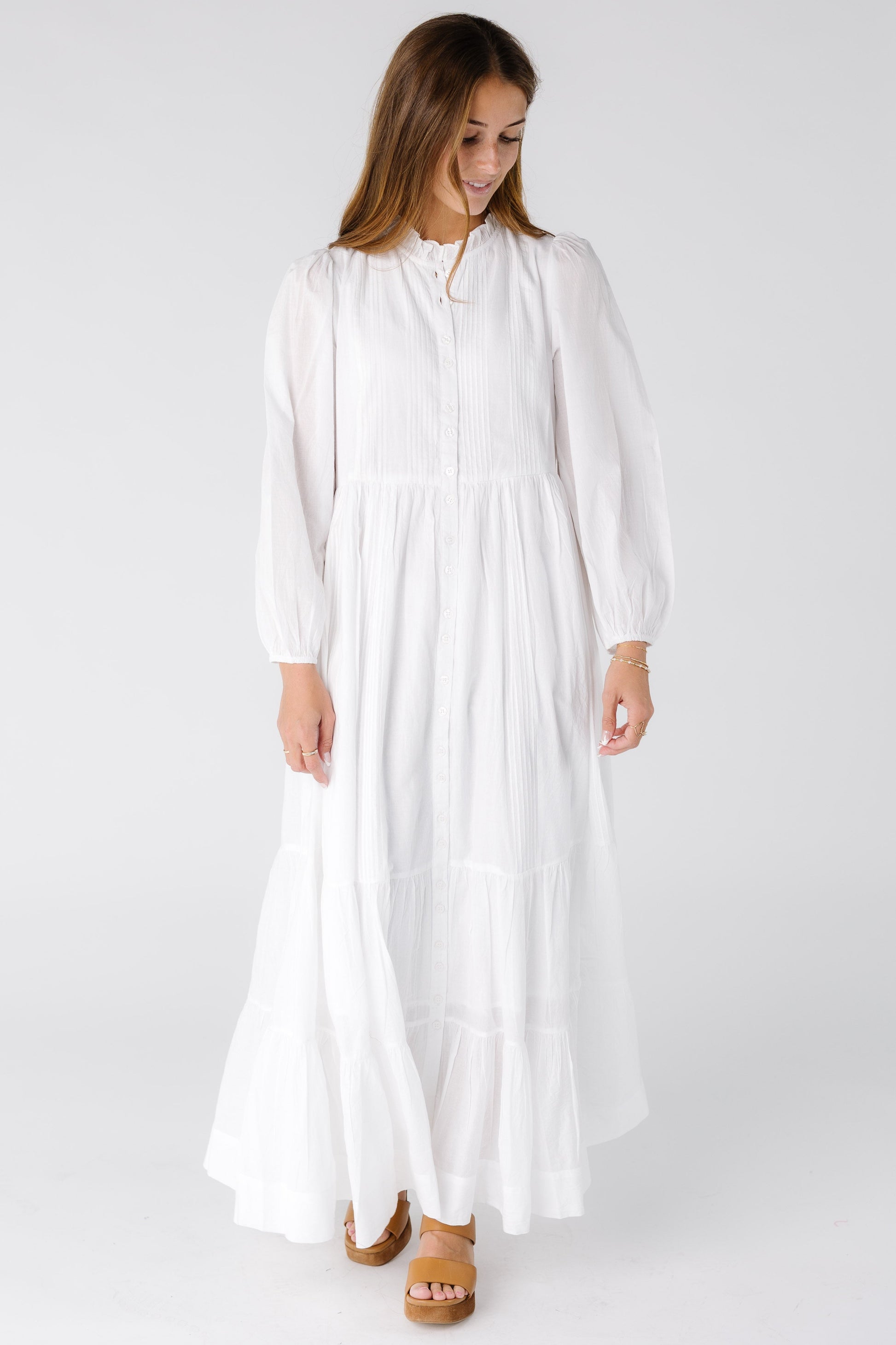 Woman wearing a white maxi dress with a high neckline and long sleeves