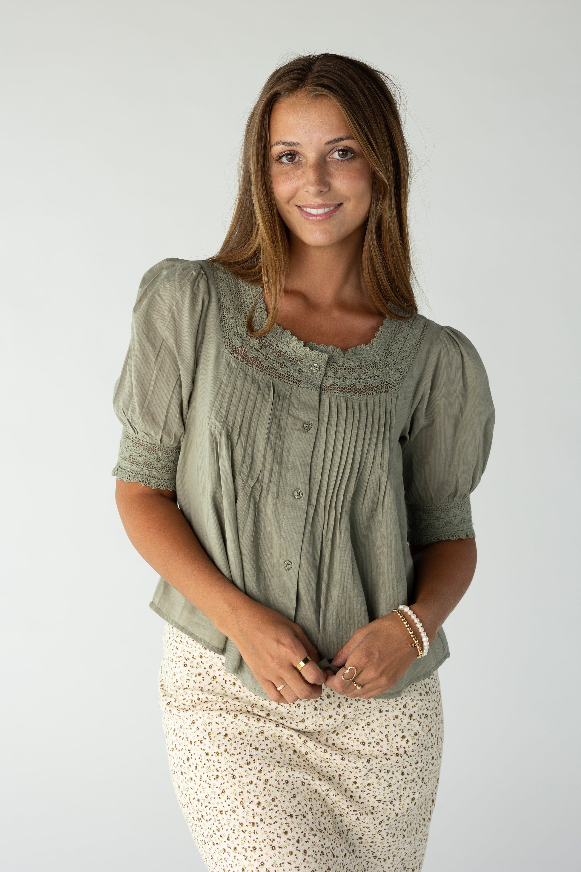 Woman wearing an olive blouse with lace and pintuck details