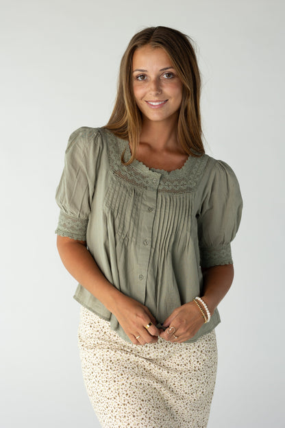 Woman wearing an olive blouse with lace and pintuck details