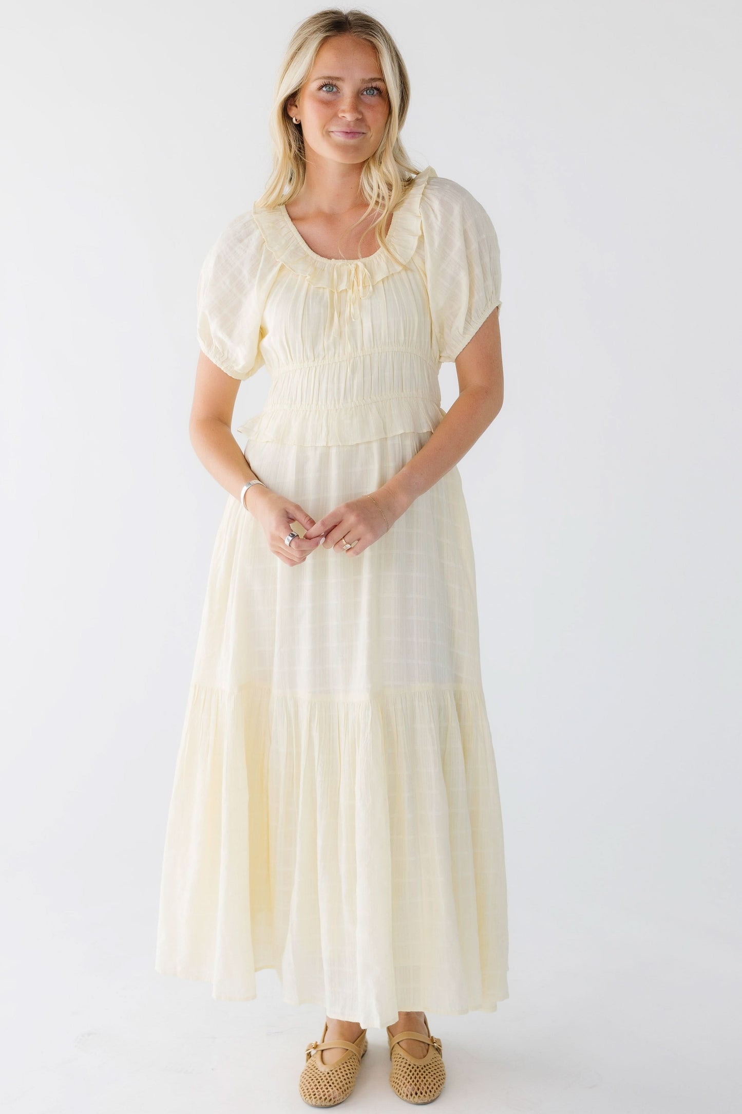 Woman wearing a light yellow midi-maxi dress with a scop neckline and puff sleeves.