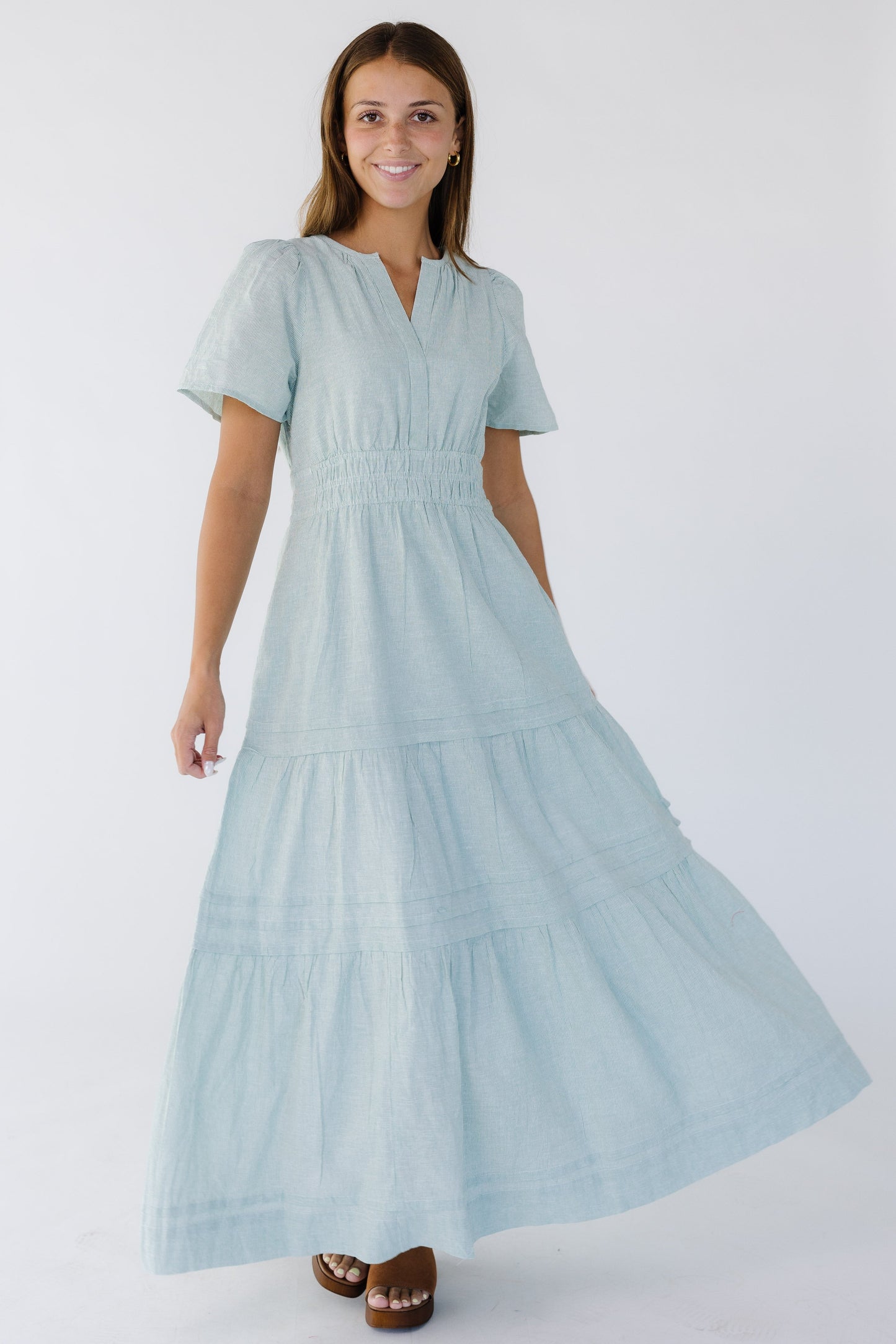 Young woman wearing a green and white stripe midi-maxi dress with a V-neckline, short sleeves, wide 3 band elastic waist and a full gathered and pleated skirt.