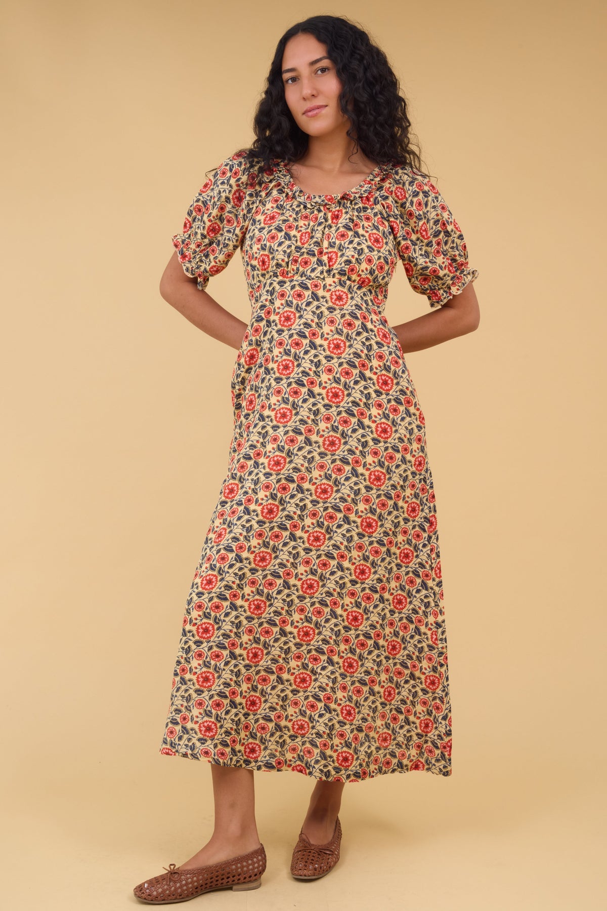 Young woman wearing a modest  floral print midi dress with an empire waist, gathered bodice, short sleeves and a ruffled scooped neckline.