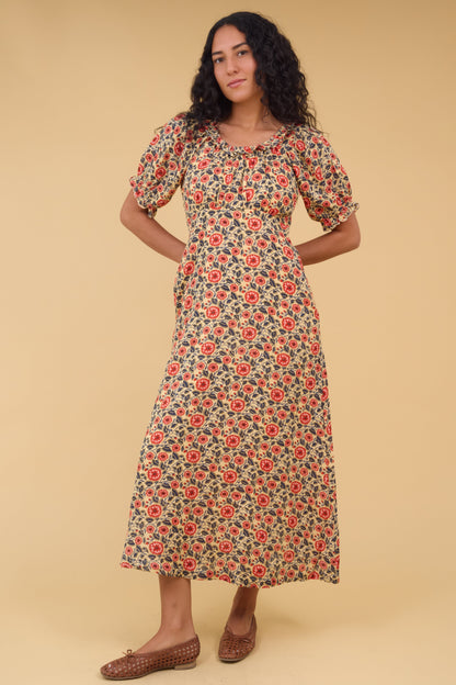 Young woman wearing a modest  floral print midi dress with an empire waist, gathered bodice, short sleeves and a ruffled scooped neckline.