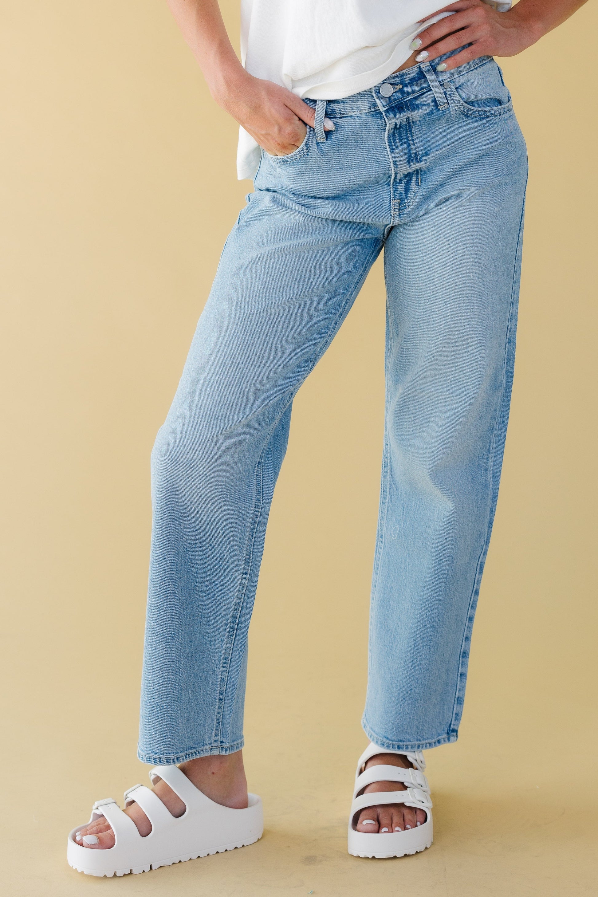 Young woman wearing a modest pair of straight leg jeans in light denim.