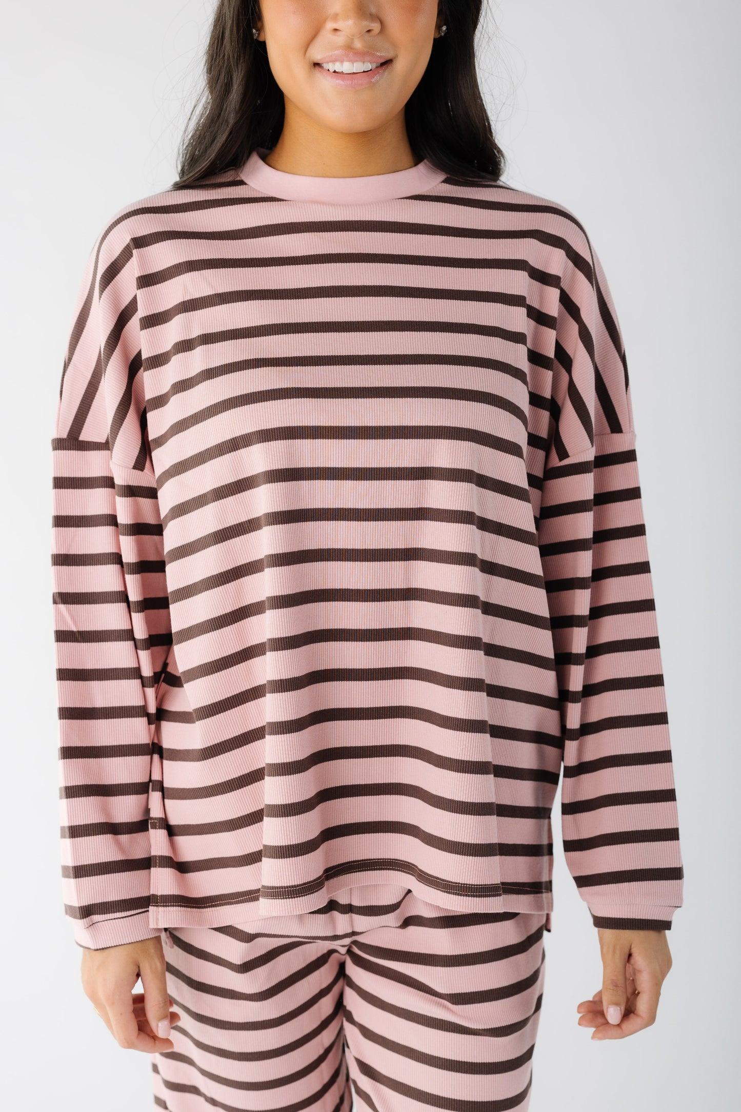 Close up view of a young woman wearing a pink and brown loose fitting lounge set.