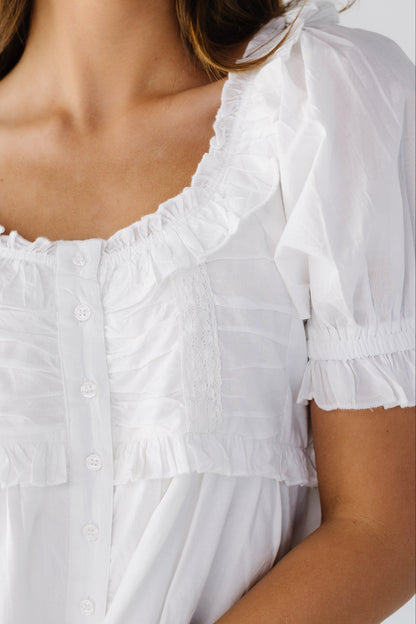 Close view of a white button down blouse with lace and ruffle details.
