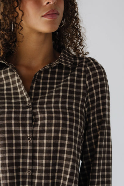 Close view of a teenage girls wearing a brown laid dress with a pointed collar.