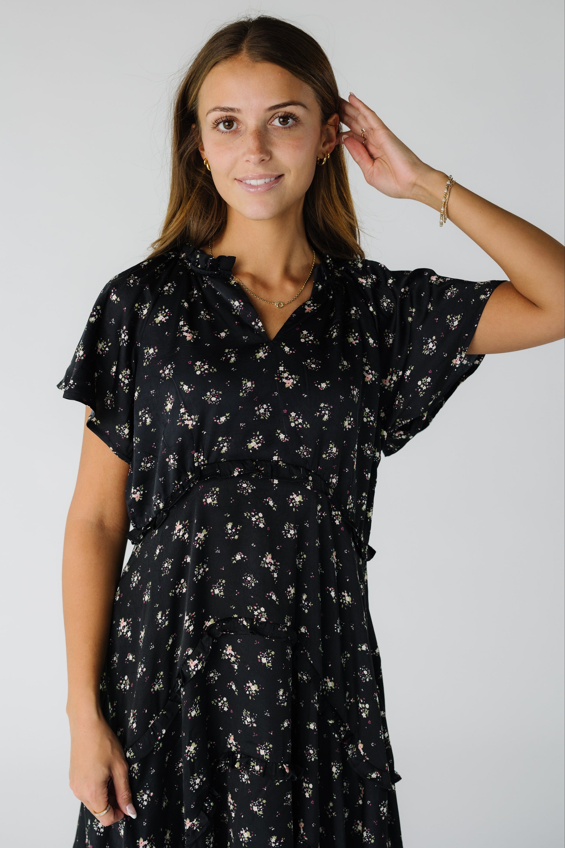 Close view of a woman wearing a black floral dress with a V-neckline and short flutter sleeves