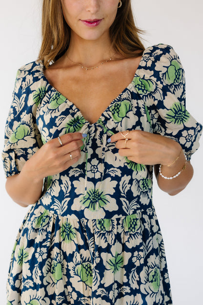 Close up view of a woman wearing a blue and green floral dress with a sweetheart neckline and an pointed empire waistband and a full skirt.