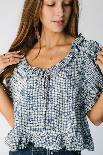 Close view of a woman wearing a blue and white plaid top with a bottom ruffle