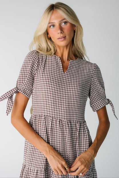 Close view of a woman wearing a brown gingham dress with short sleeves with ties