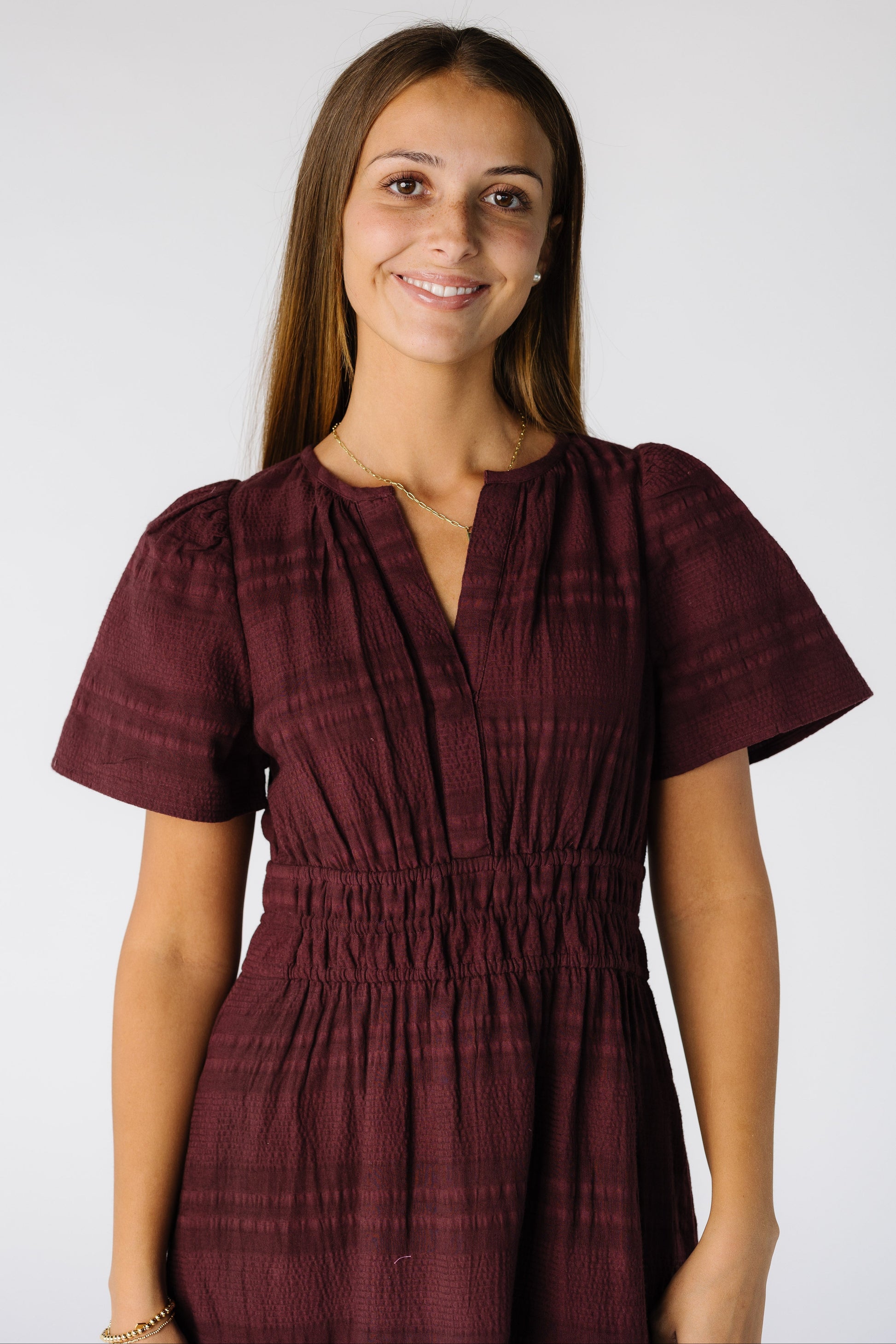 Close view of a woman wearing a burgundy dress with short sleeves and a V-neckline 